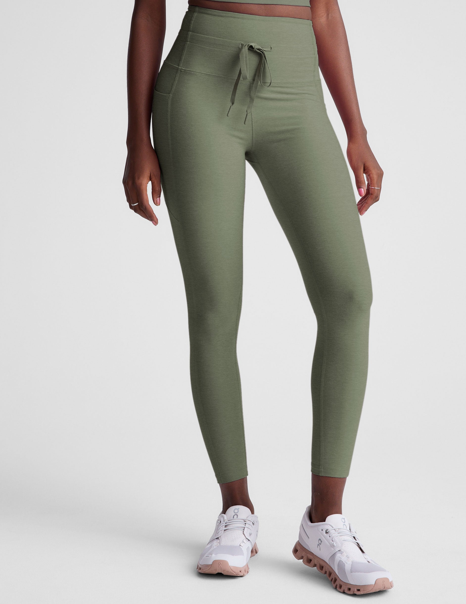 green high-waisted midi length leggings with pockets and a drawstring at waistband.