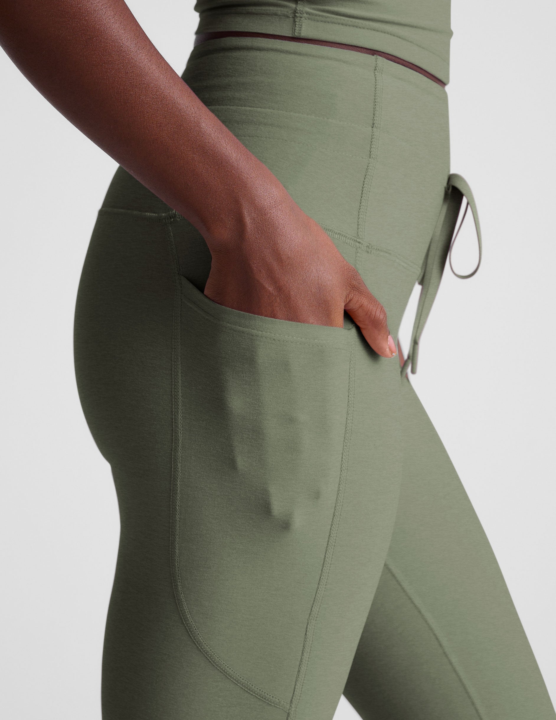 green high-waisted midi length leggings with pockets and a drawstring at waistband.