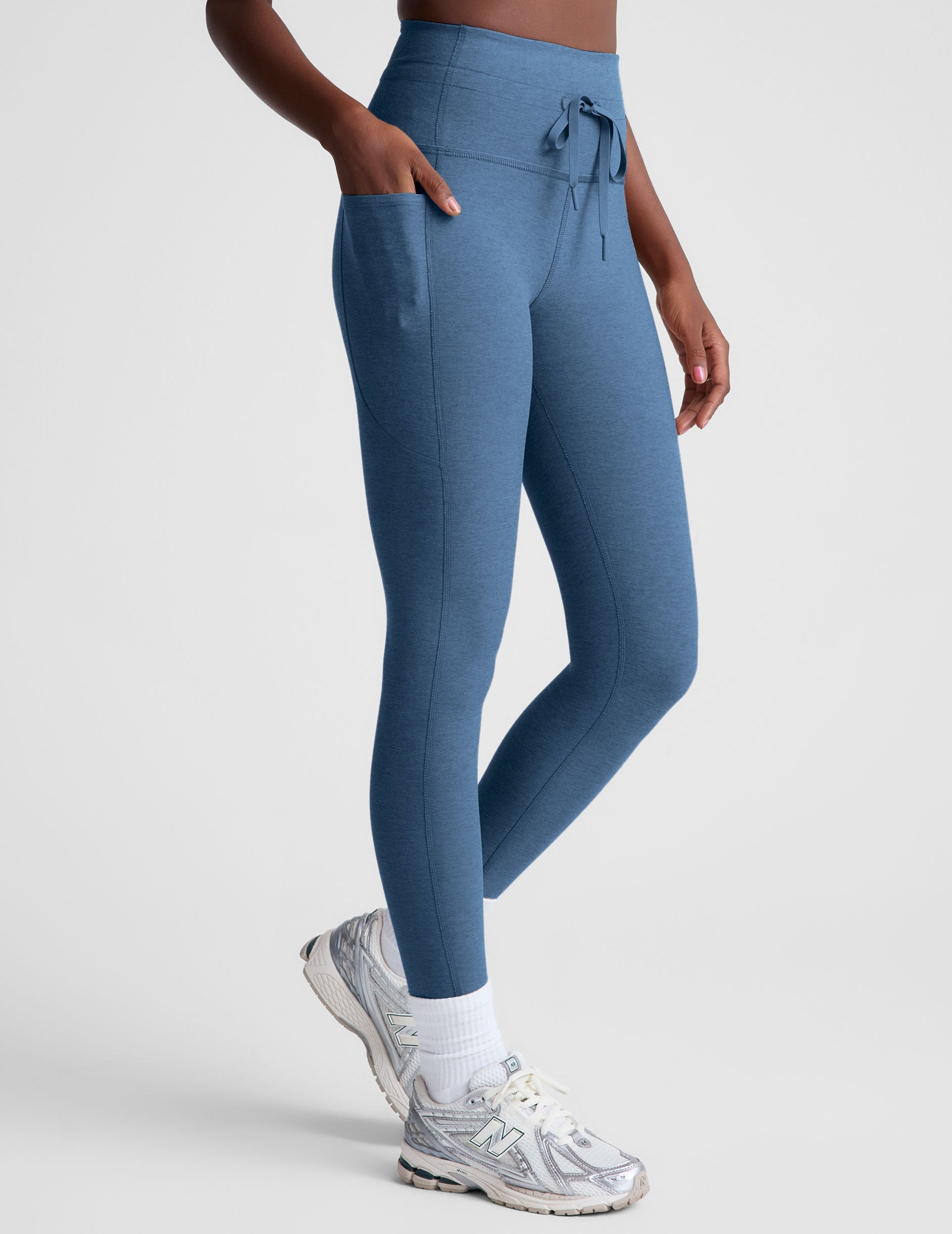 blue high-waisted midi leggings with pockets and a drawstring at waistband.