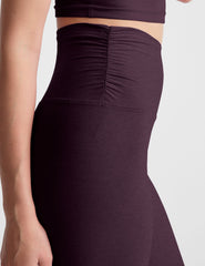purple high-waisted midi length leggings against a plain background.