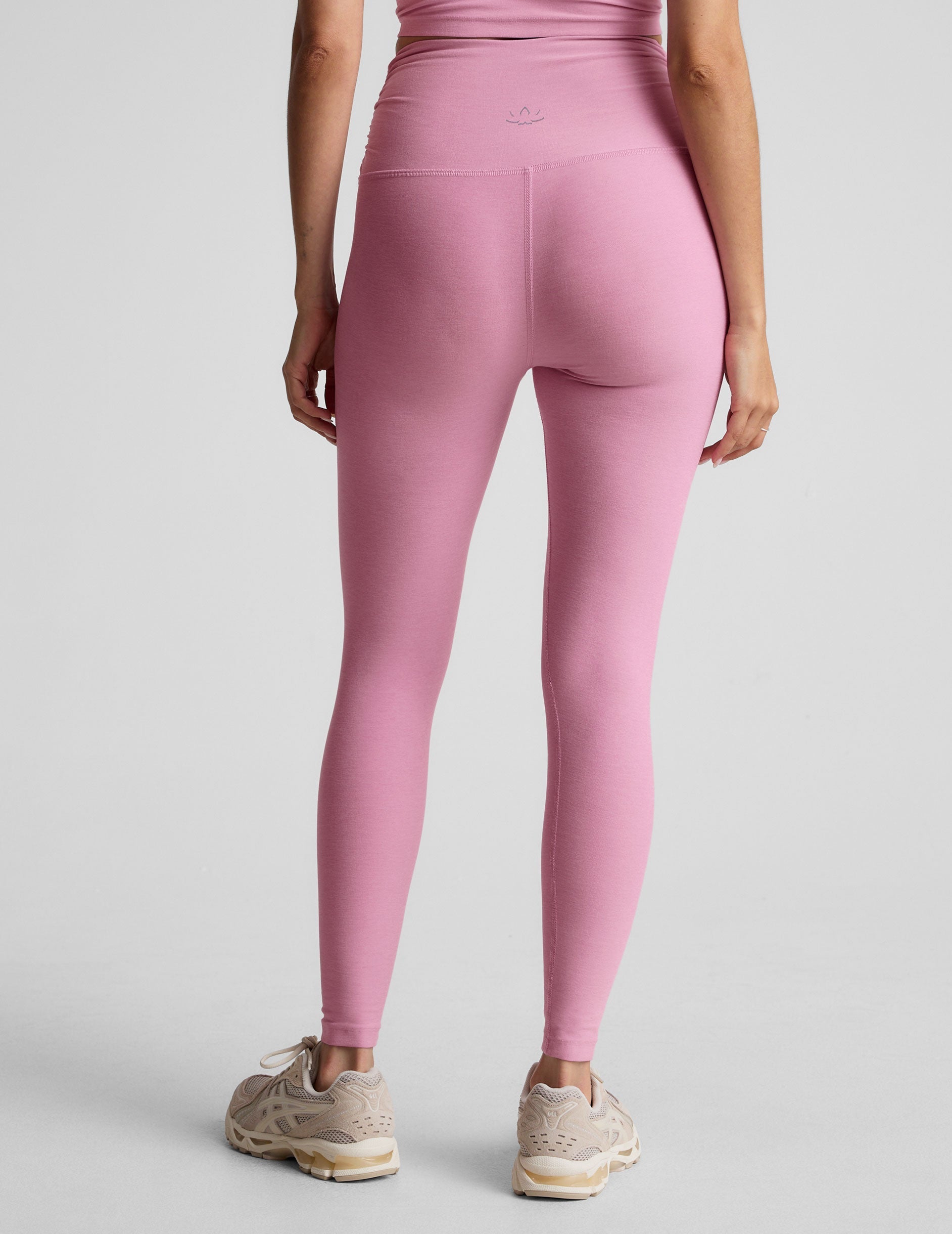 pink high-waisted midi length leggings with shirred detailing on the side of each waistband.