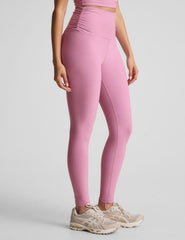 pink high-waisted midi length leggings with shirred detailing on the side of each waistband.