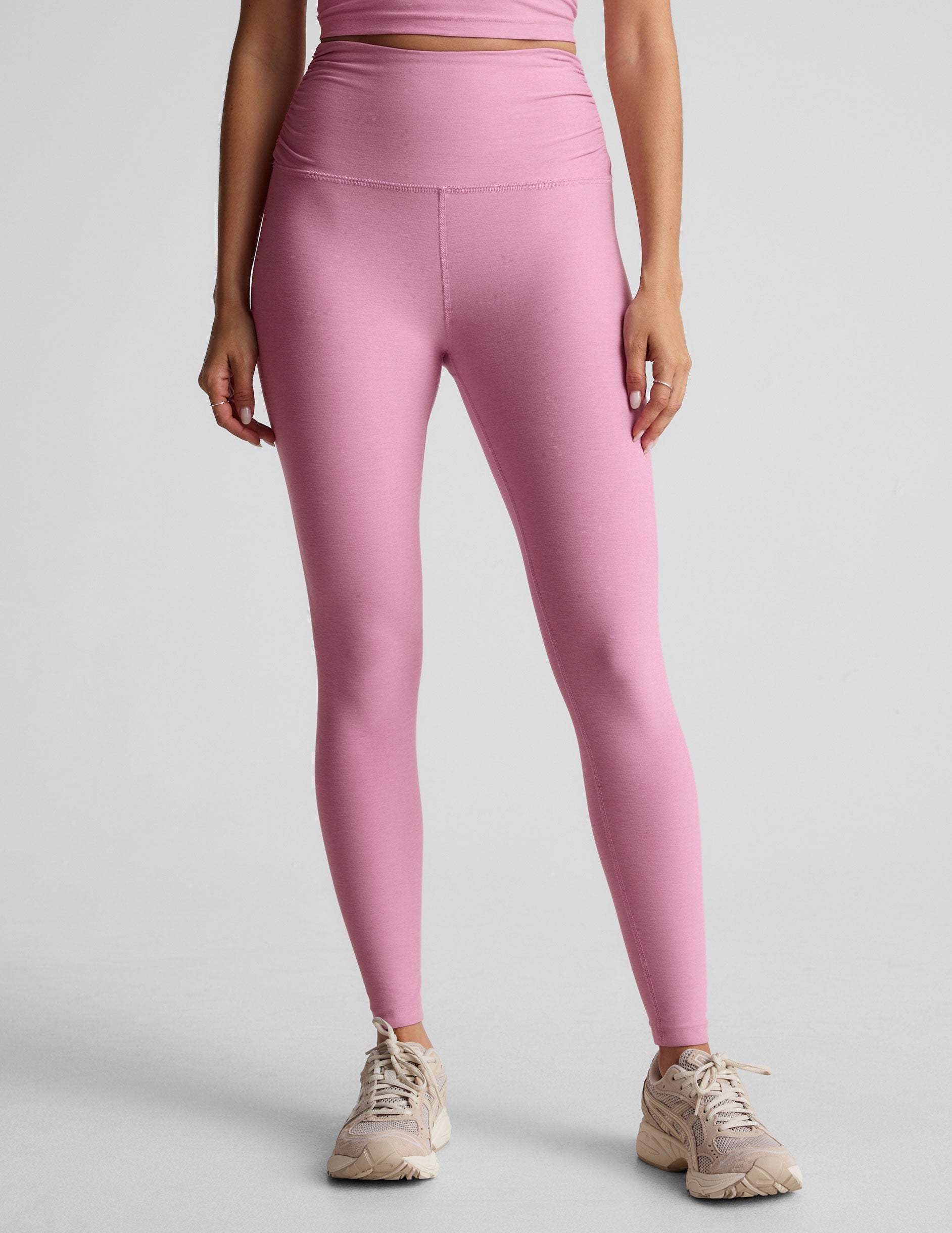 pink high-waisted midi length leggings with shirred detailing on the side of each waistband.