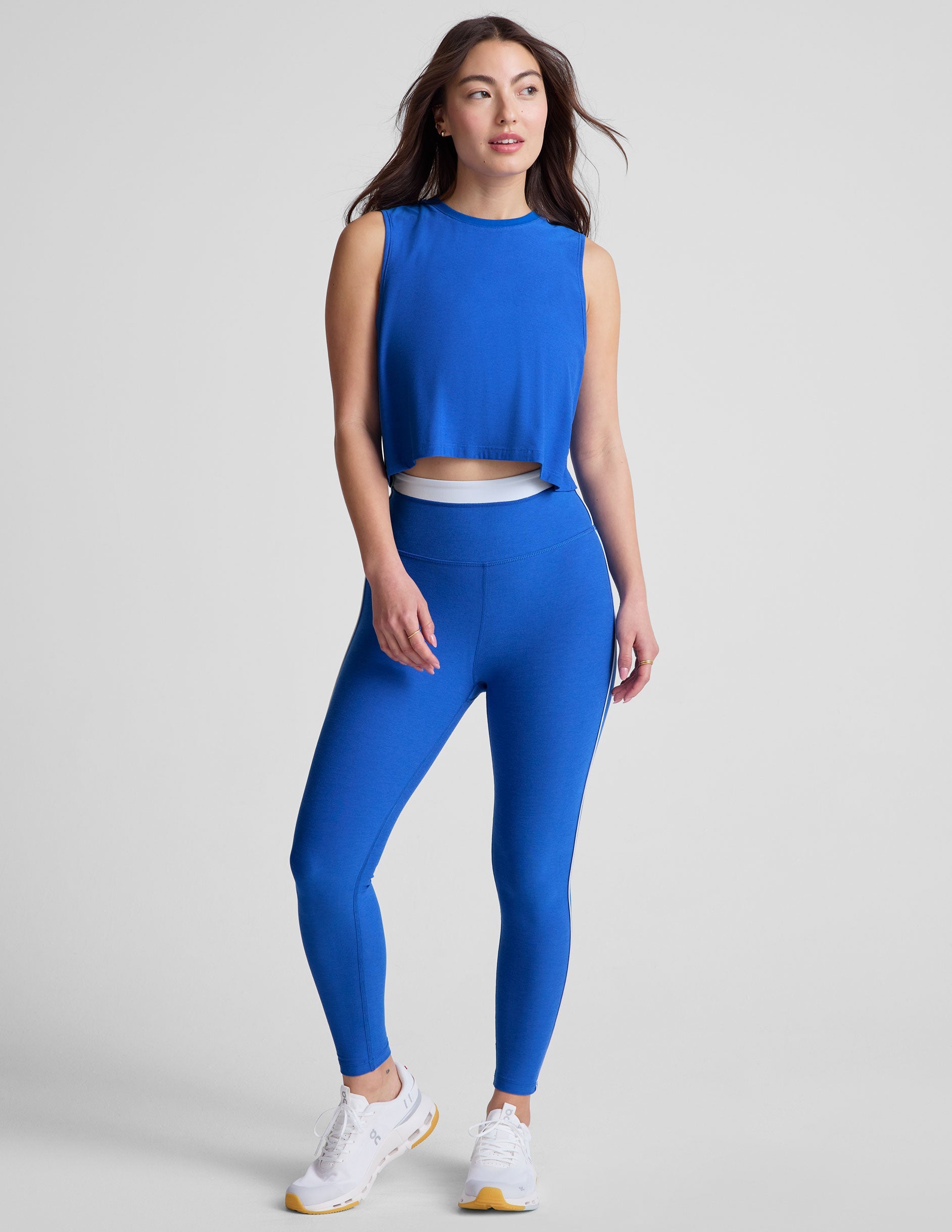 blue high-waisted midi leggings with white contrast piping on side of leg and around waistband.