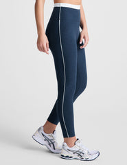 navy blue high-waisted midi leggings with white contrast piping on side of leg and around waistband.