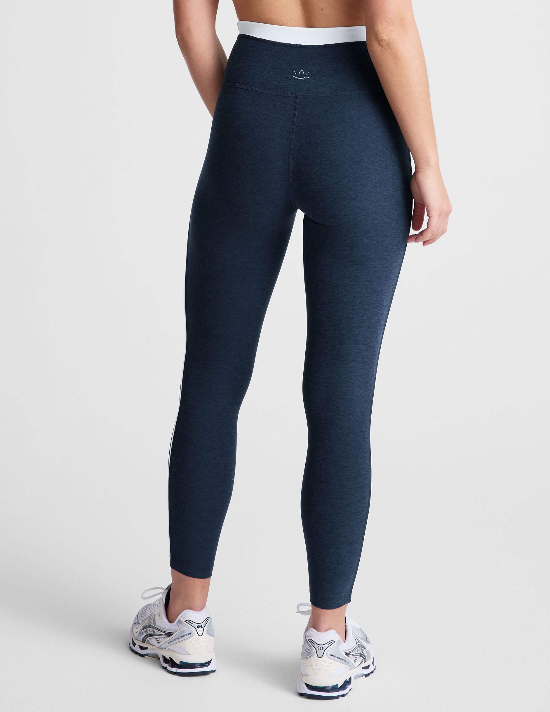 navy blue high-waisted midi leggings with white contrast piping on side of leg and around waistband.
