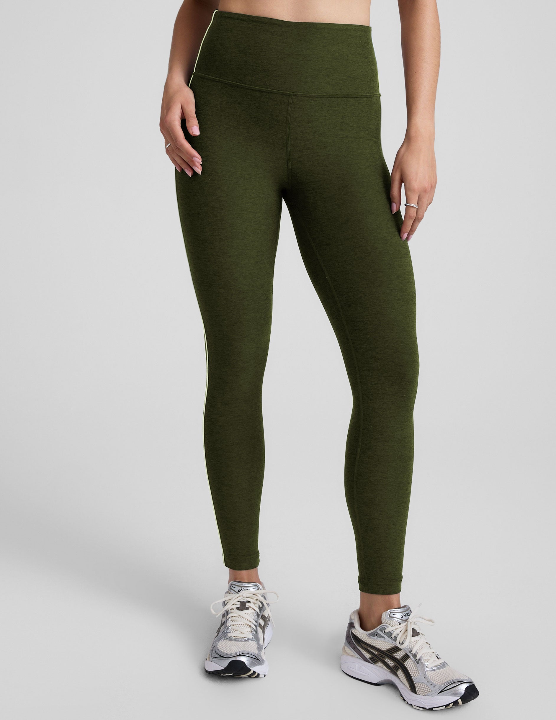 green high-waisted midi length leggings with white piping along sides.