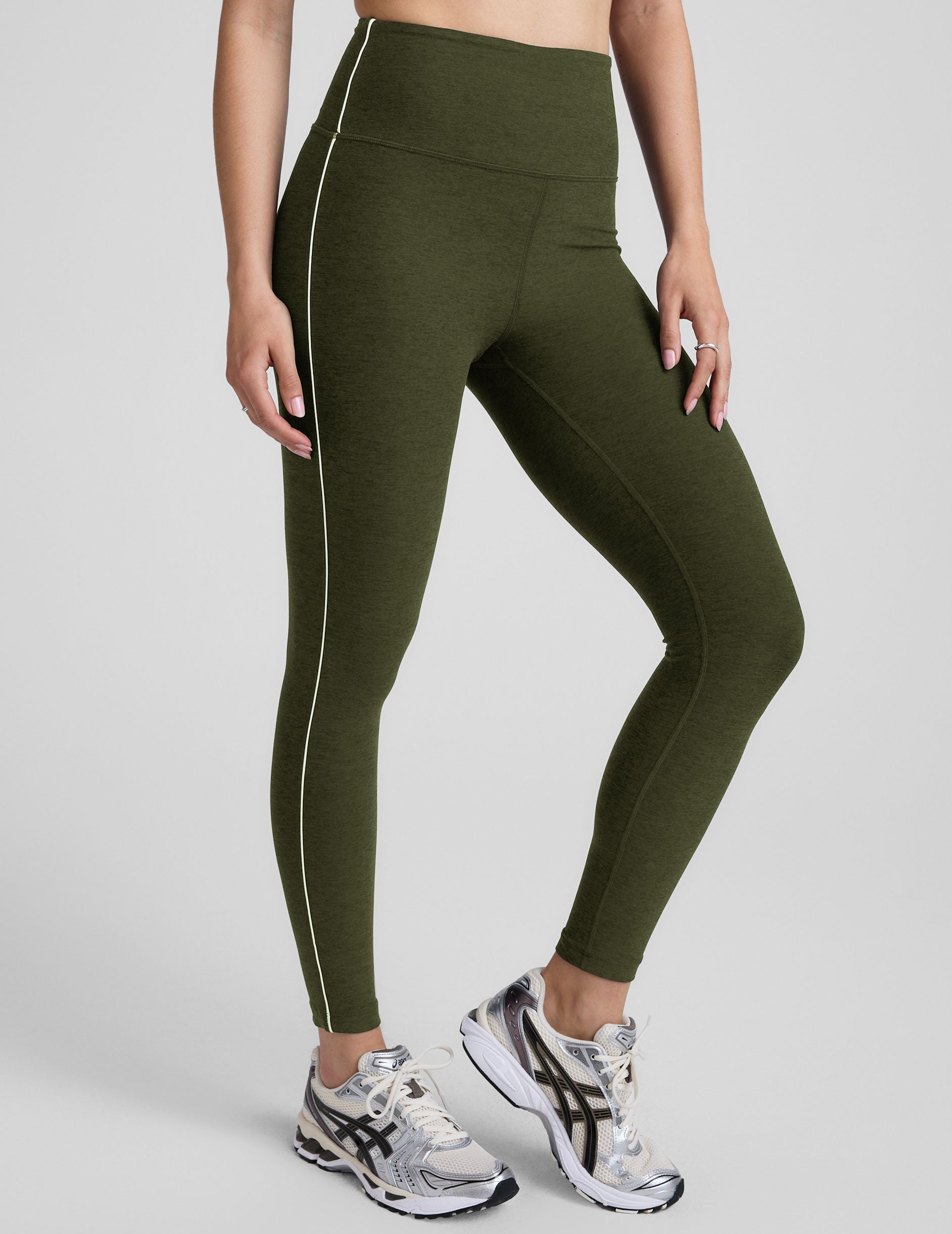 green high-waisted midi length leggings with white piping along sides.