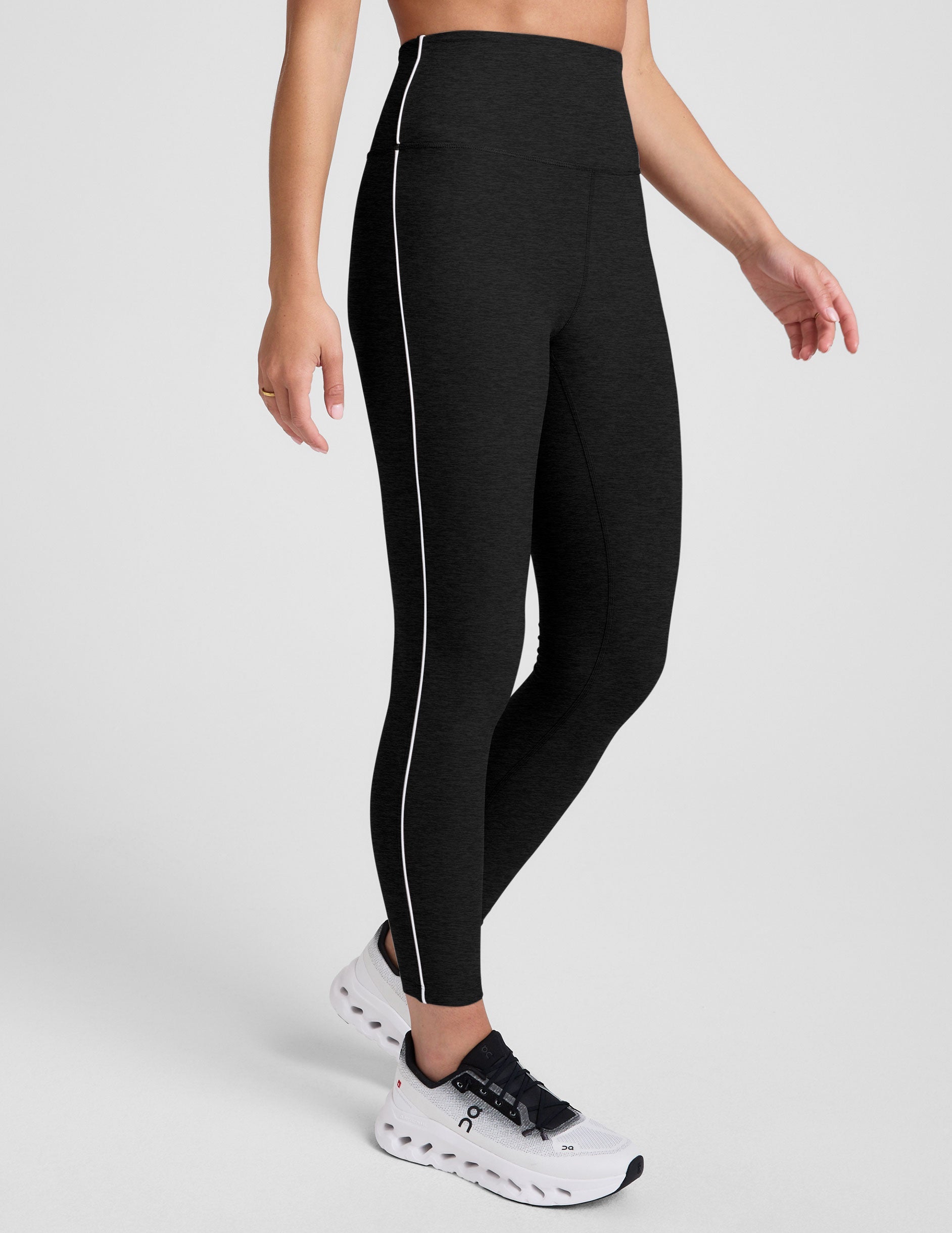 black high-waisted midi length leggings with white contrast piping at sides.