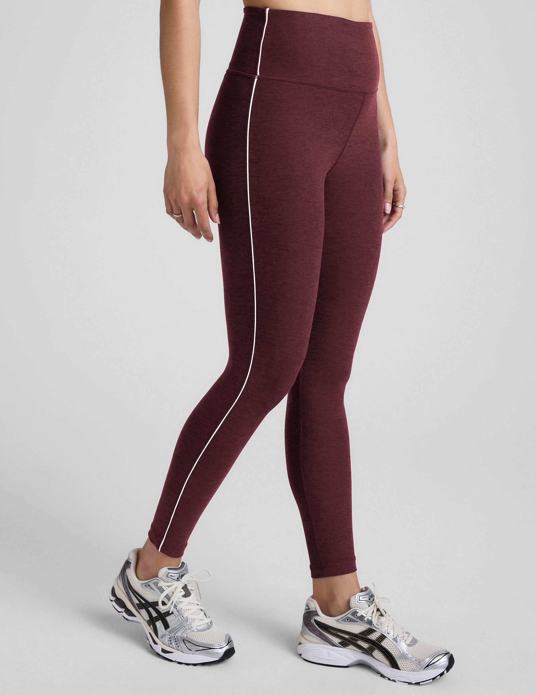 burgundy leggings with a white stripe on a gray background.