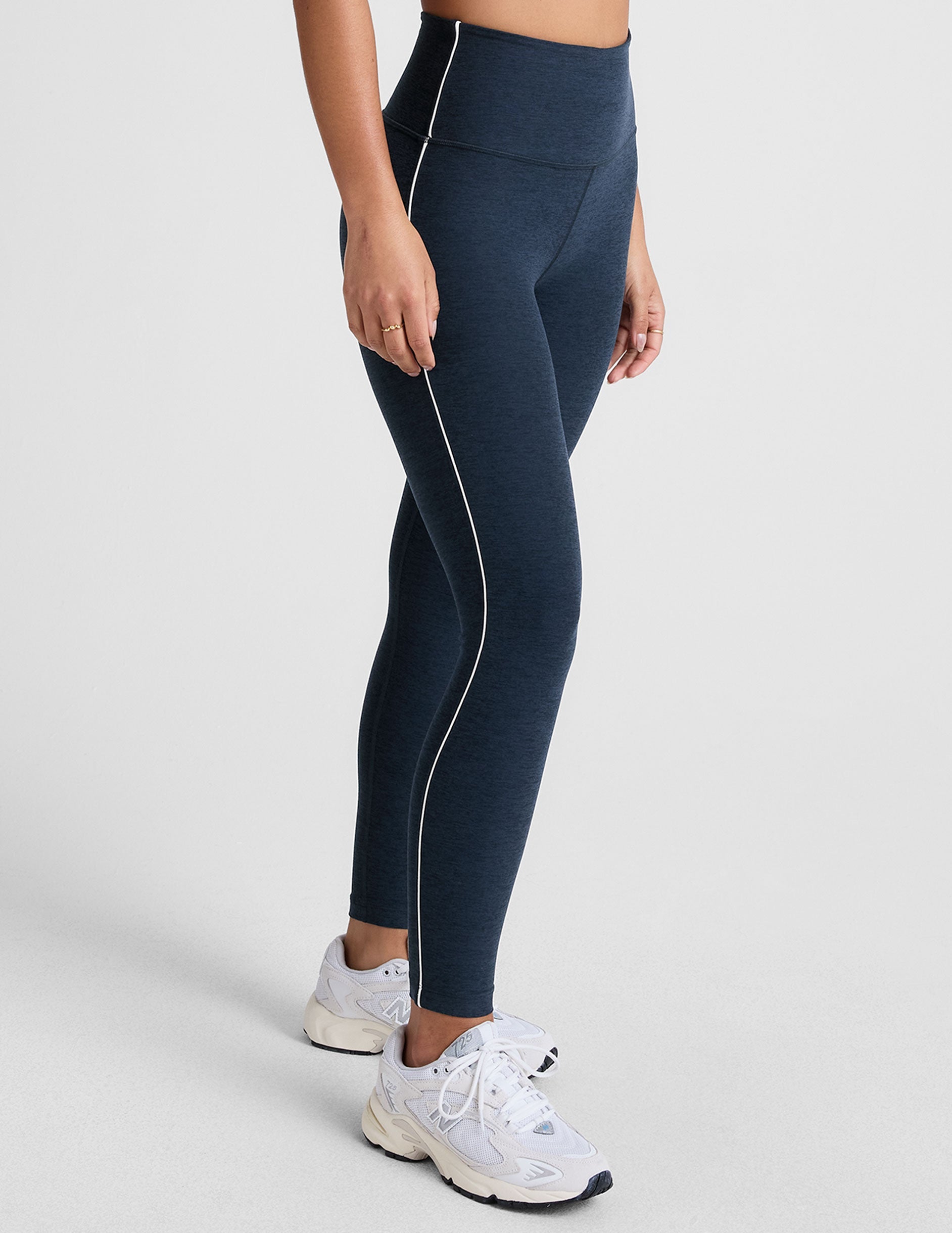 blue high-waisted midi length leggings with white piping on the side.