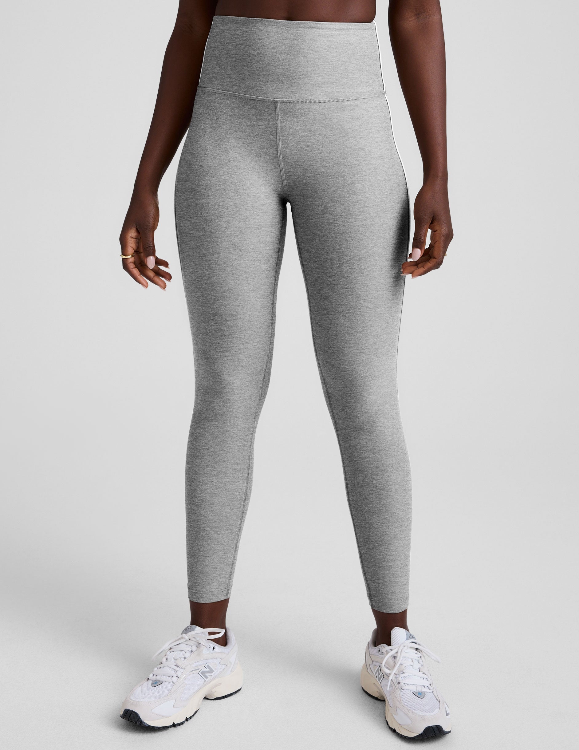 grey high-waisted midi length leggings with white piping details on sides.