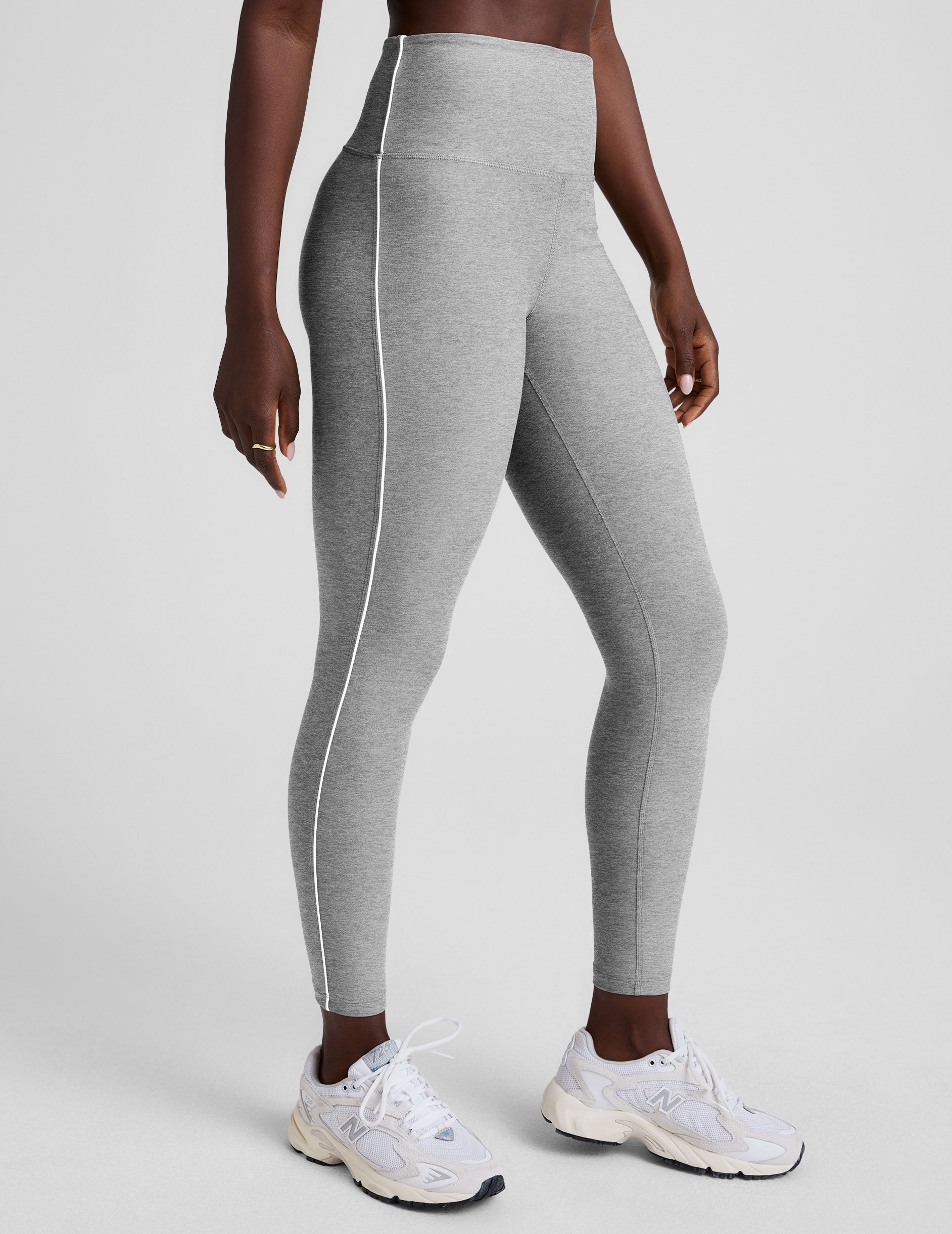 grey high-waisted midi length leggings with white piping details on sides.