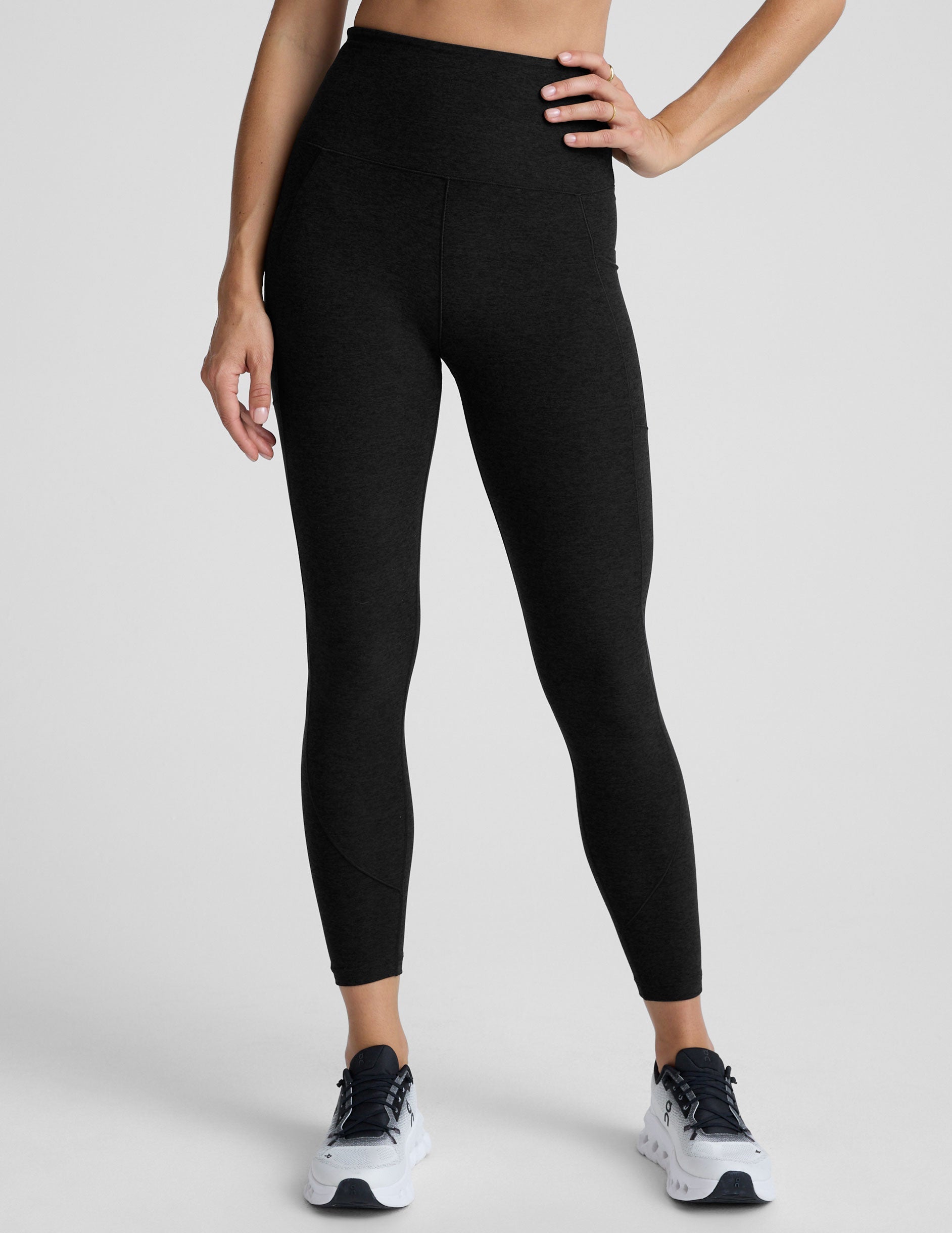 model wearing black midi length leggings with 3 pockets against a plain background.