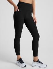 model wearing black midi length leggings with 3 pockets against a plain background.