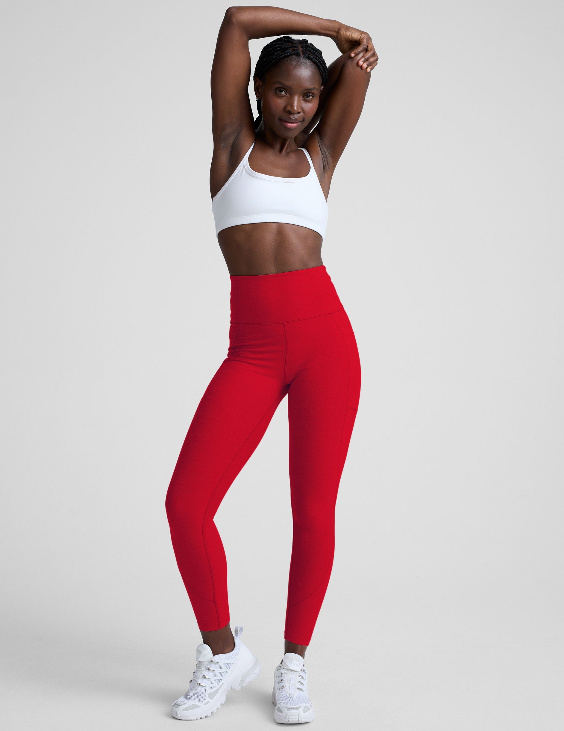 woman wearing red high-waisted pocket leggings on a plain background.