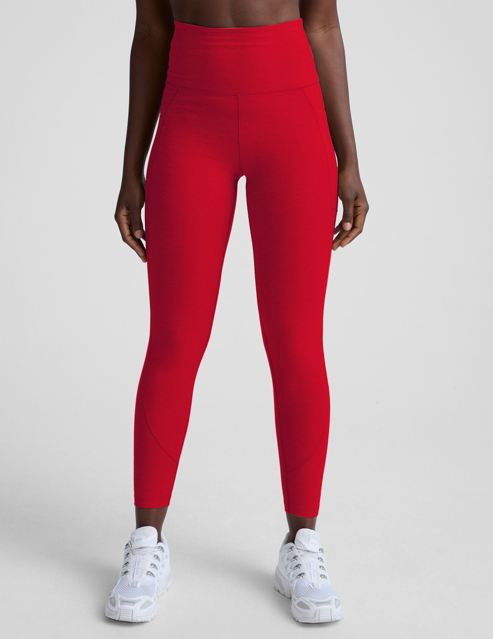 woman wearing red high-waisted pocket leggings on a plain background.