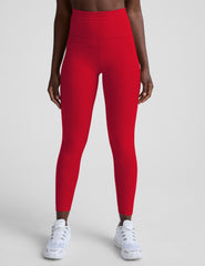 woman wearing red high-waisted pocket leggings on a plain background.