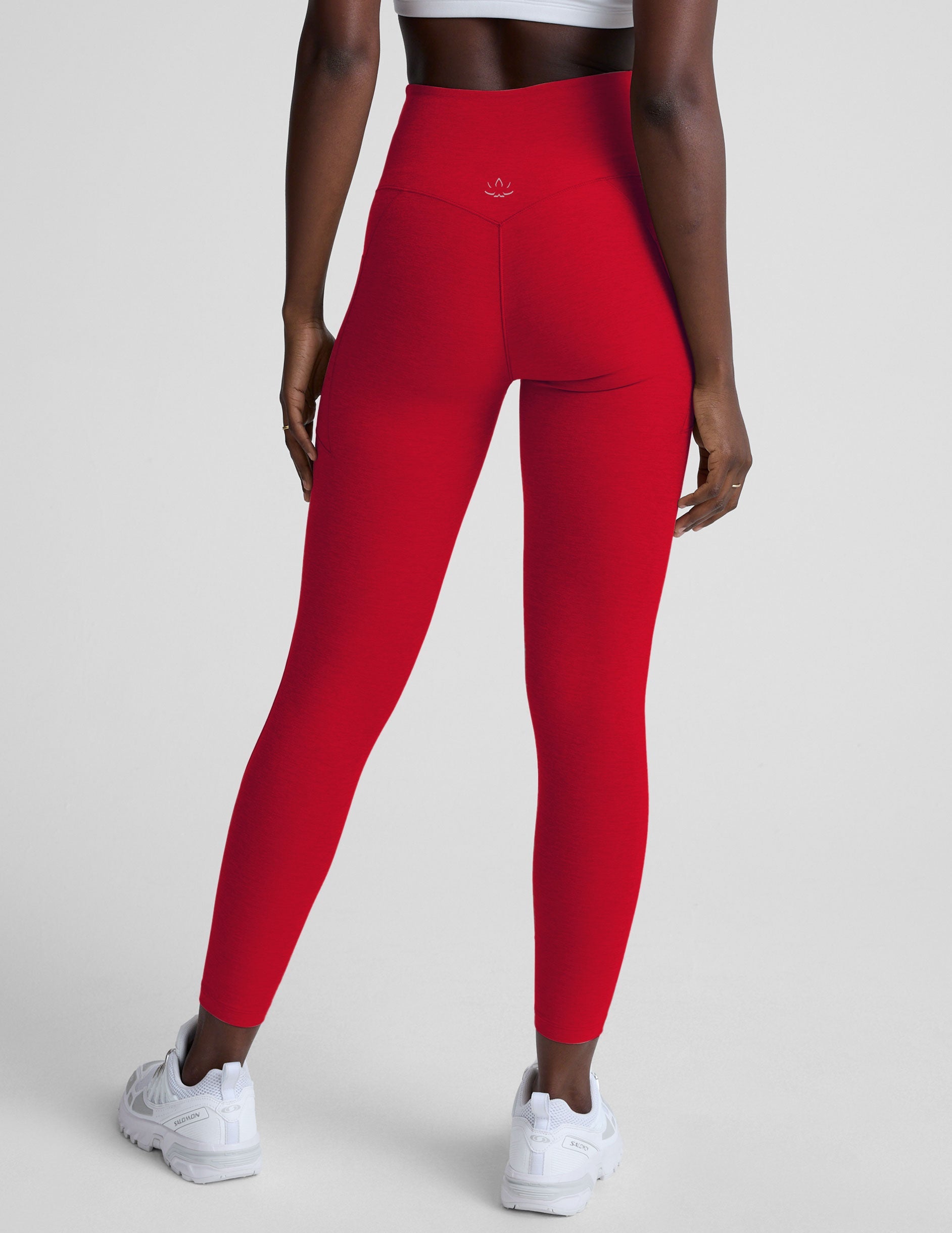 woman wearing red high-waisted pocket leggings on a plain background.