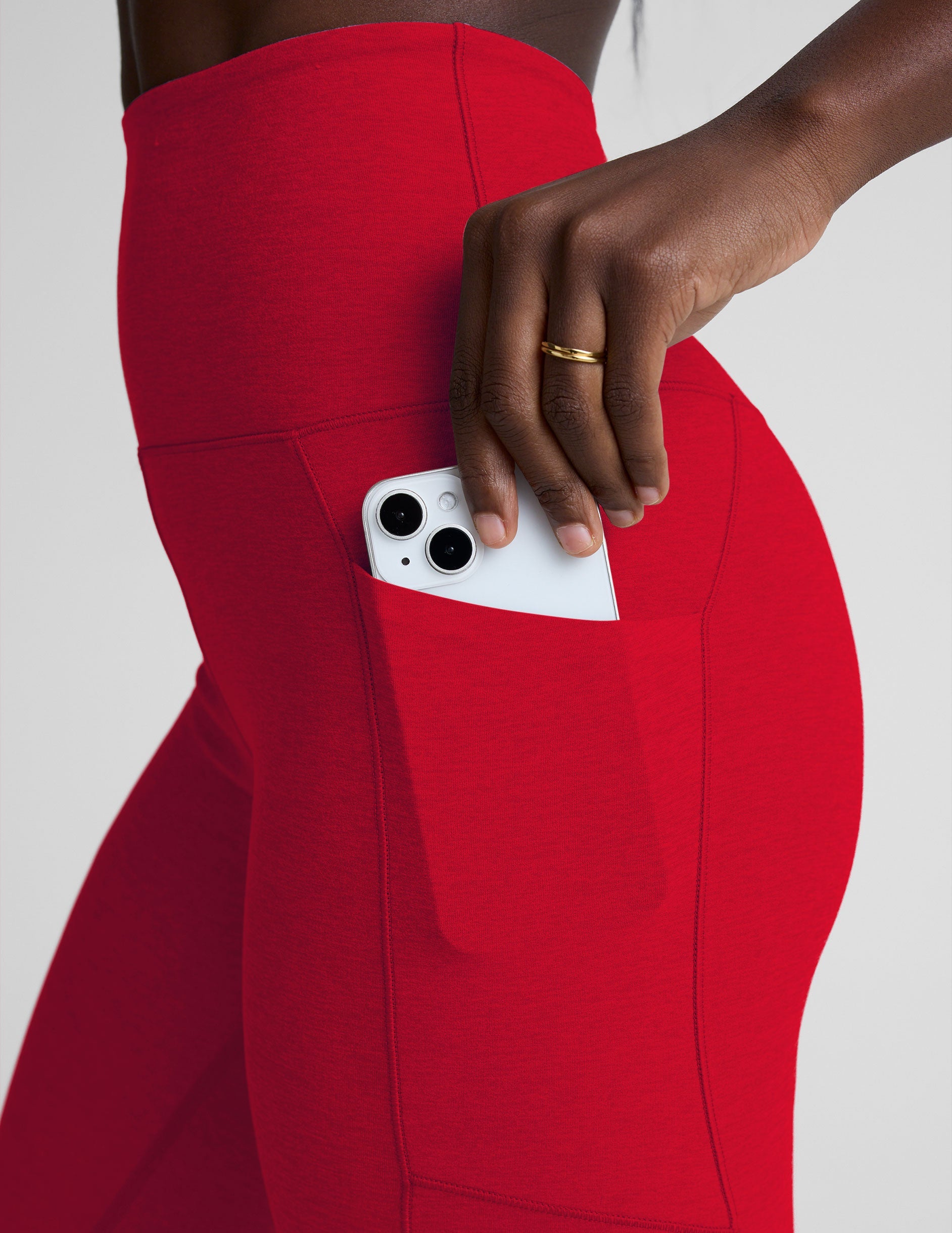 woman wearing red high-waisted pocket leggings on a plain background.