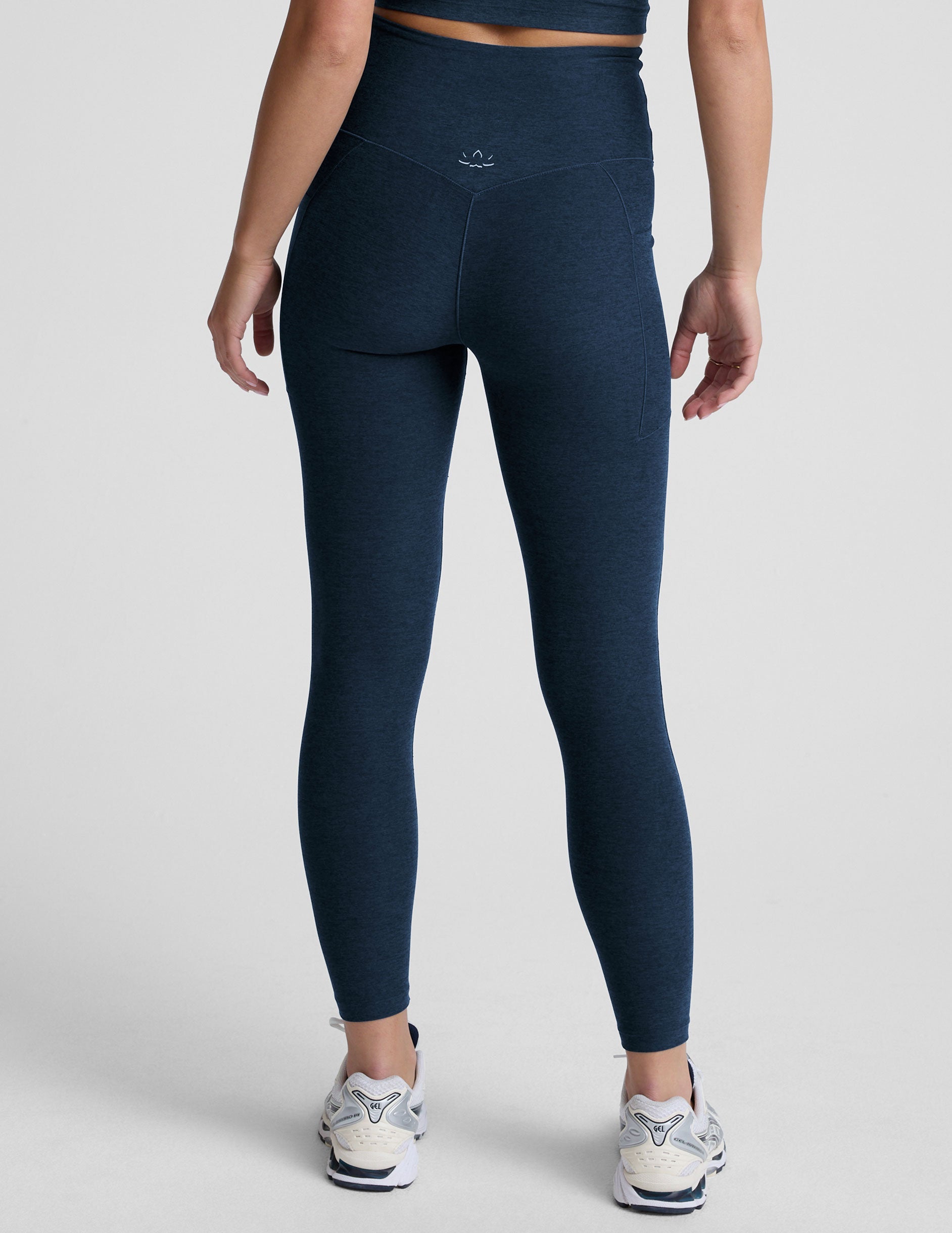 model wearing blue midi length leggings with 3 pockets against a plain background.