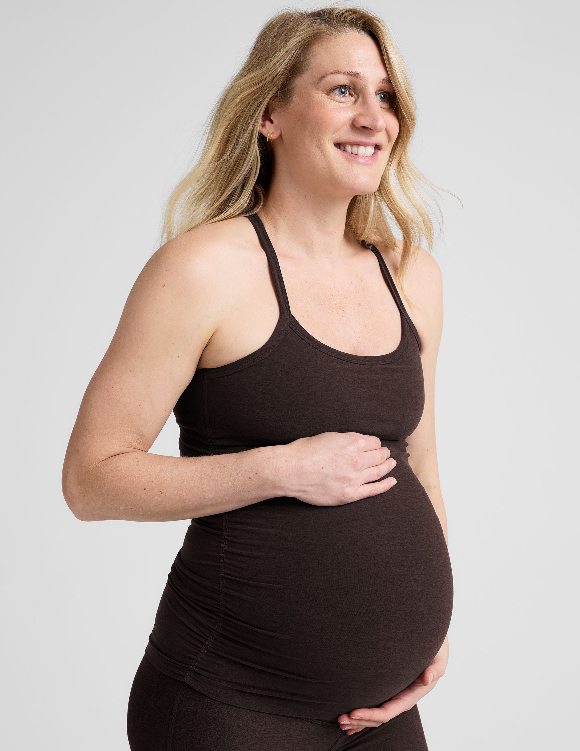 model wearing a brown maternity racerback tank top against a plain background.