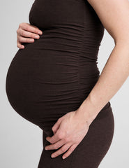 model wearing a brown maternity racerback tank top against a plain background.