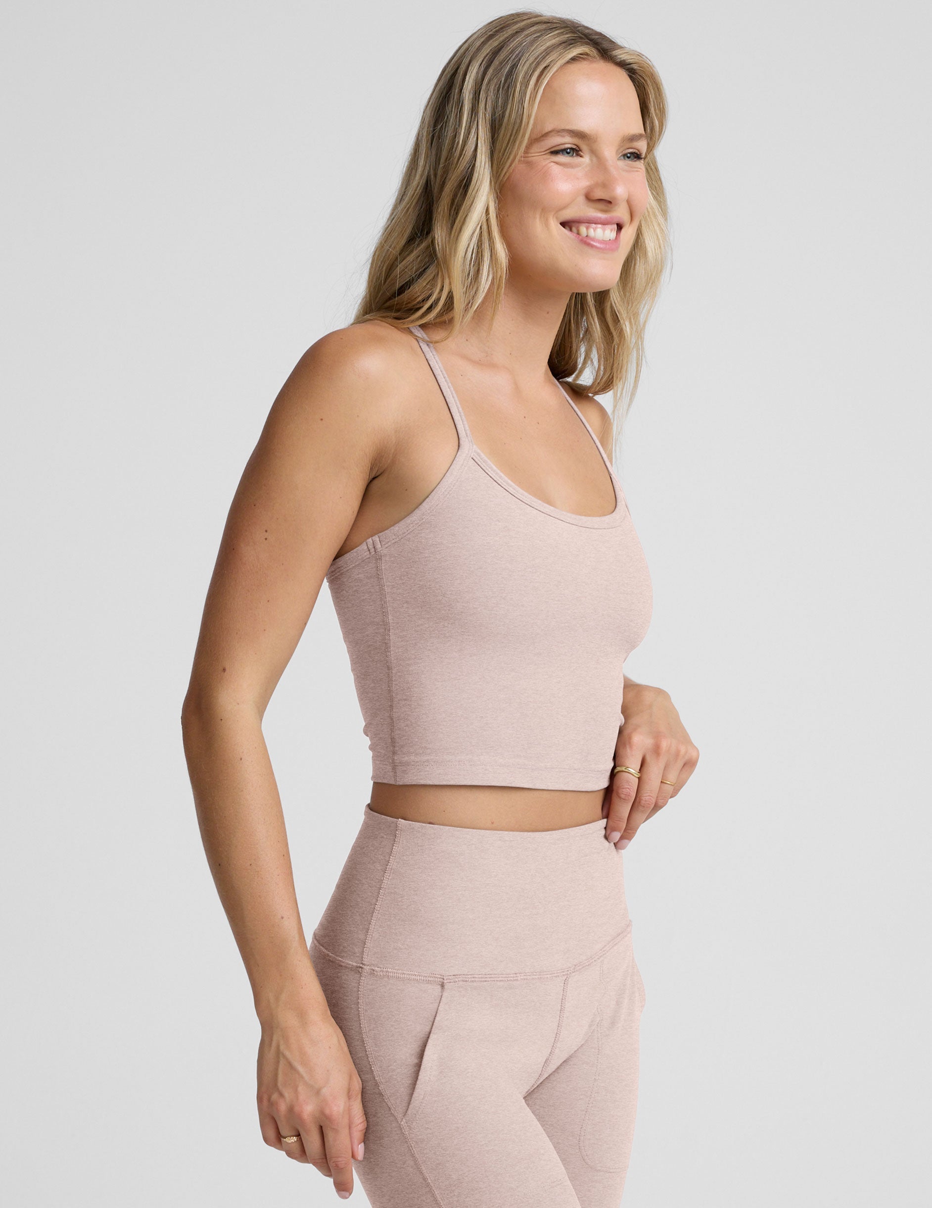pink slim racerback cropped tank top and pink high-waisted midi leggings on a plain background.