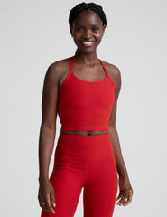 woman wearing a red slim racerback cropped tank and leggings against a plain background.