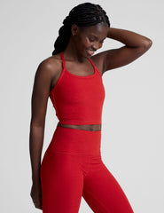 woman wearing a red slim racerback cropped tank and leggings against a plain background.