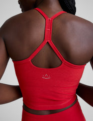woman wearing a red slim racerback cropped tank and leggings against a plain background.