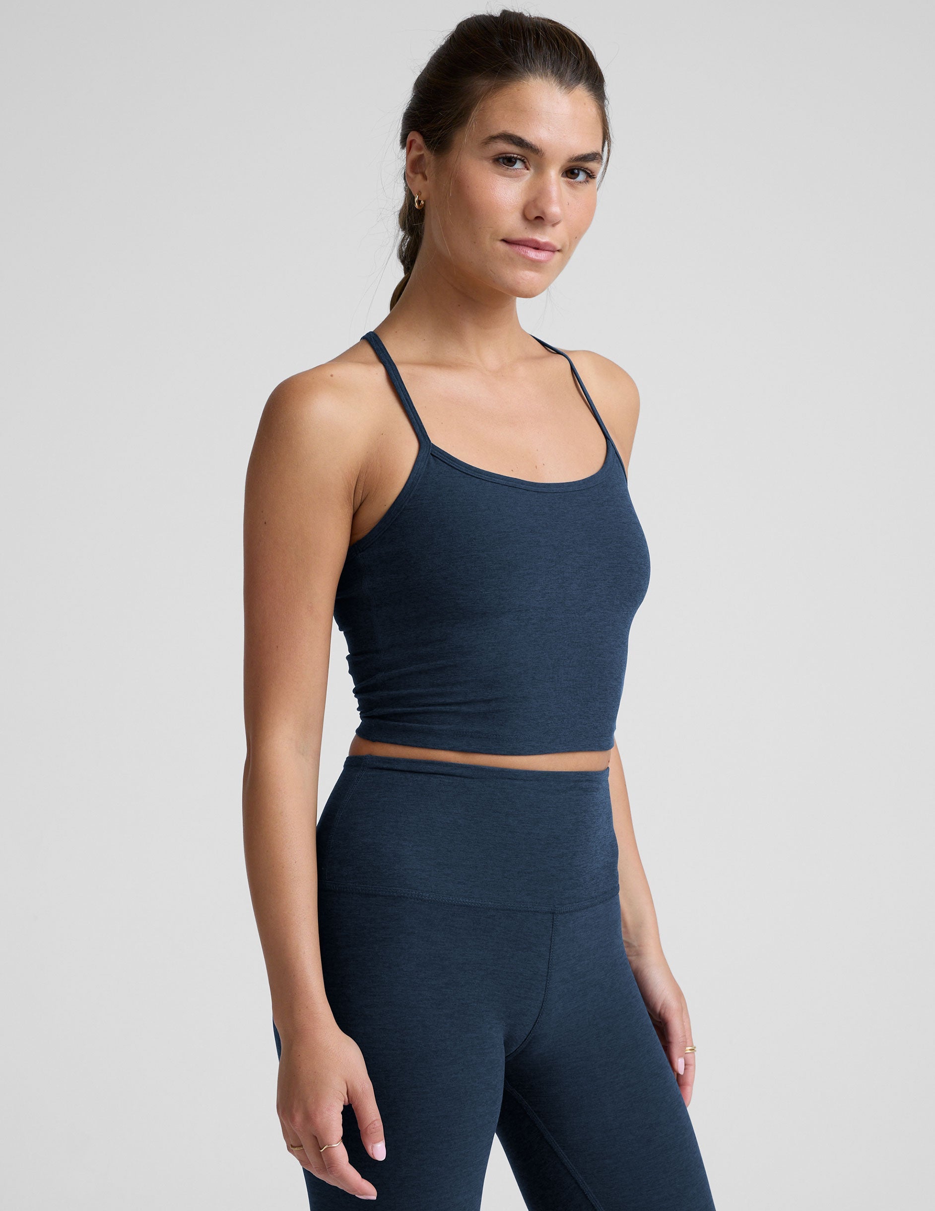woman wearing a navy blue racerback cropped tank and leggings on a plain background.