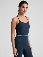woman wearing a navy blue racerback cropped tank and leggings on a plain background.