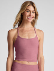 model wearing a pink racerback cropped tank top against a plain background.