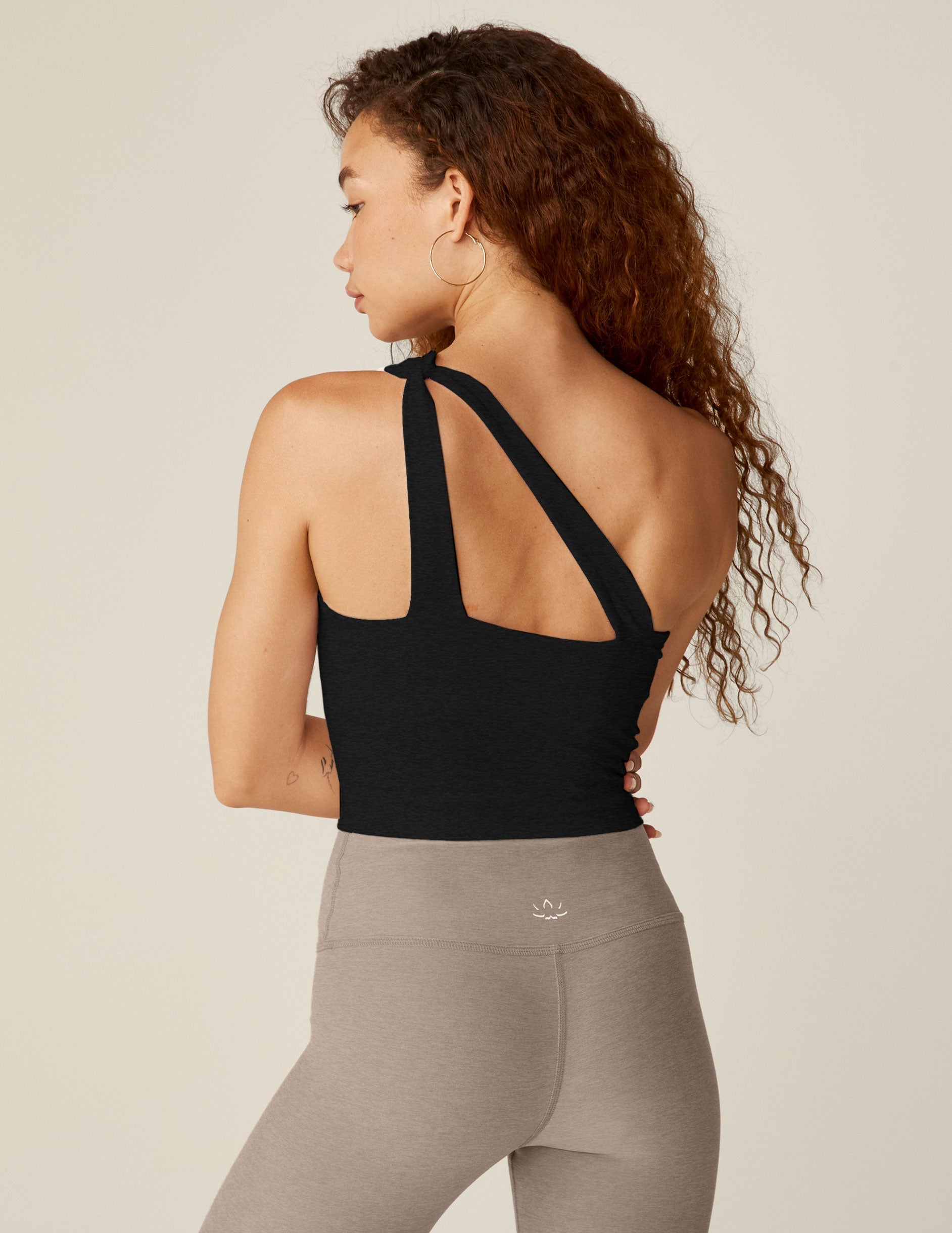 black one-shoulder cropped tank with a cutout on the front strap and a detailing on the back strap.