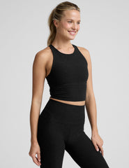 woman wearing a black high neck racerback cropped tank on a plain background.