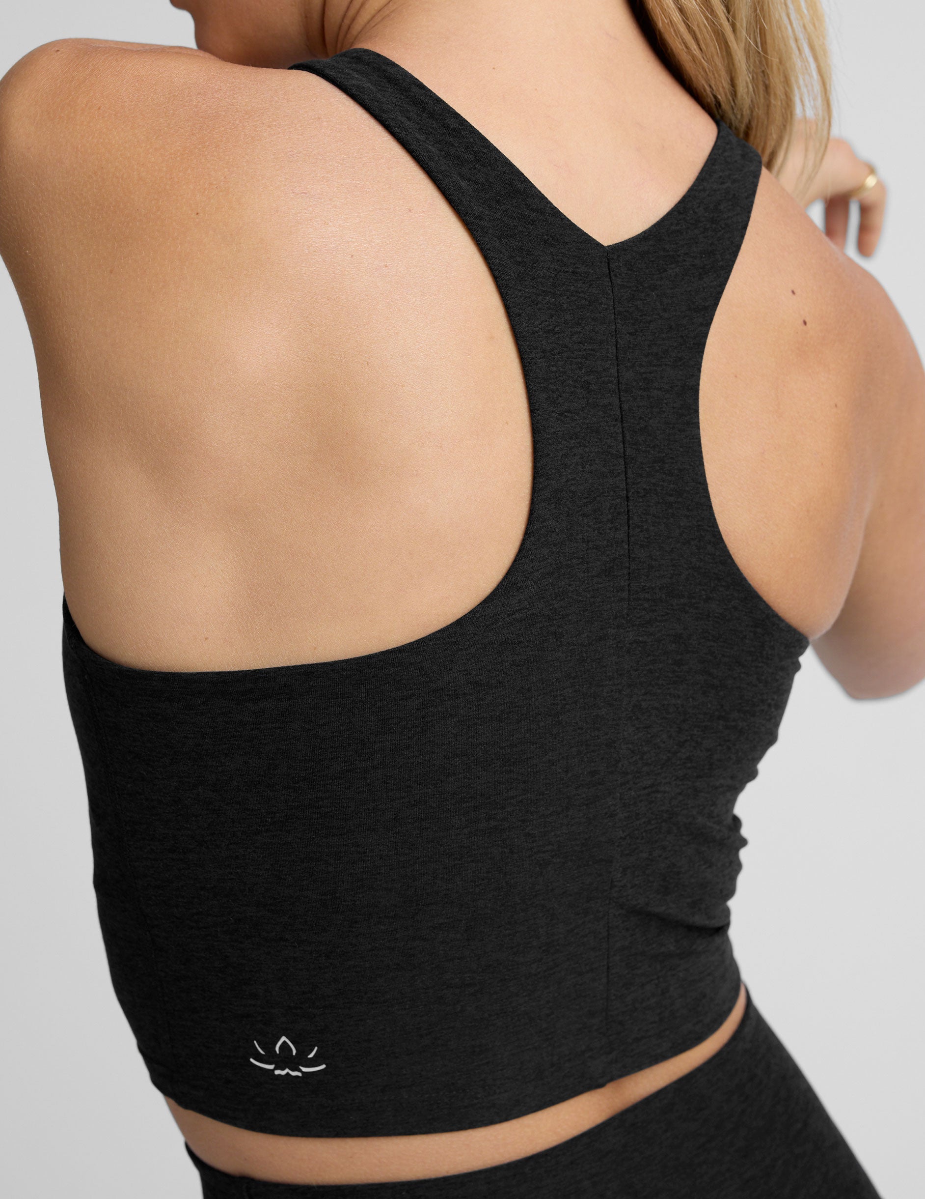 woman wearing a black high neck racerback cropped tank on a plain background.