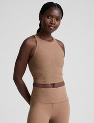 woman wearing a brown high neck racerback cropped tank top and leggings on a plain background.