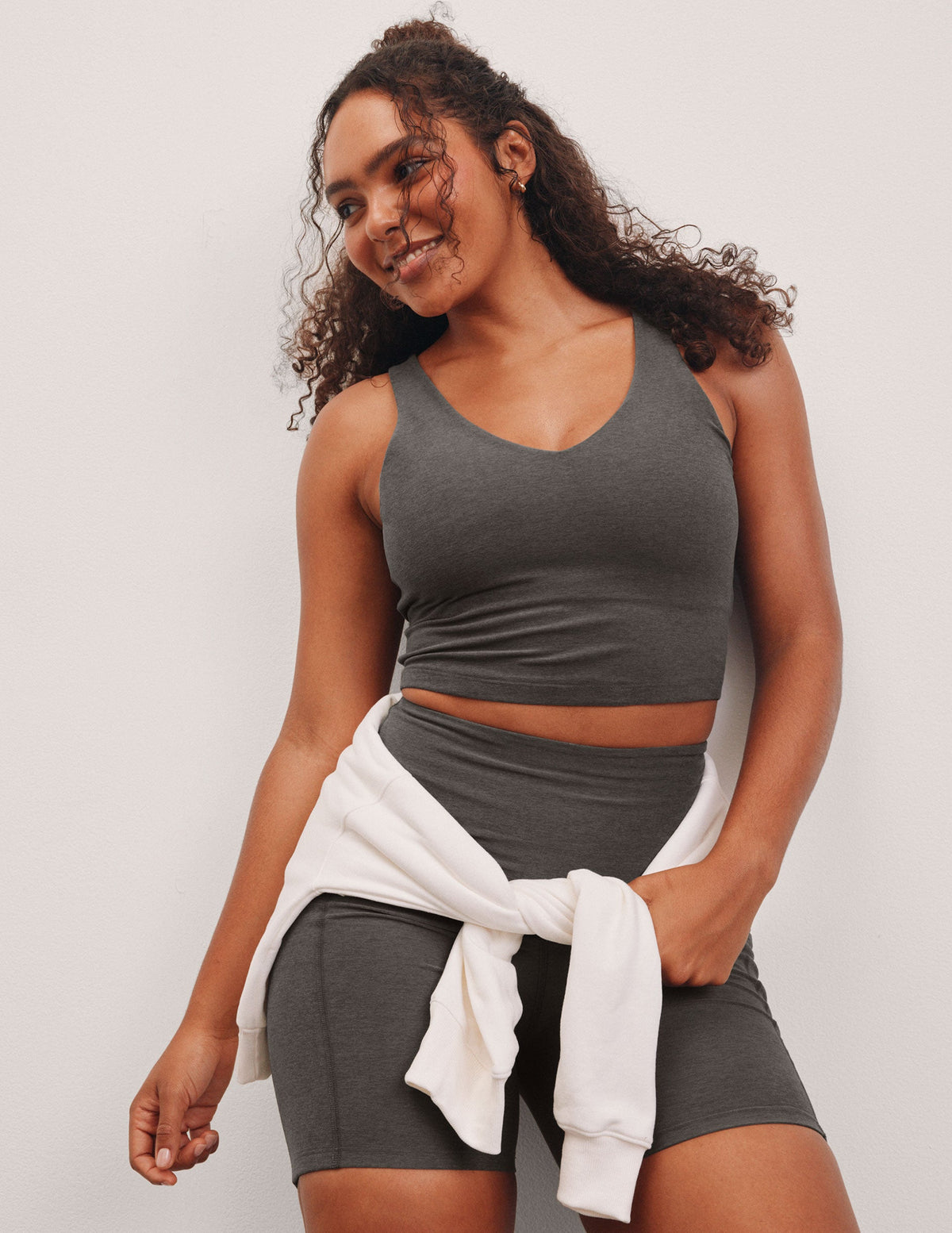 gray cropped length tank top with a front and back V neckline and self shelf bra. paired with high-waisted 5" inseam length biker shorts. 