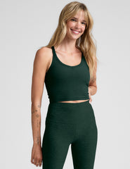 woman wearing a green v-neck racerback cropped tank and leggings on a light gray background.