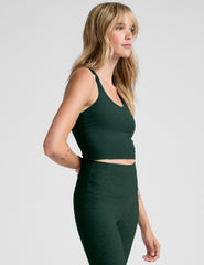 woman wearing a green v-neck racerback cropped tank and leggings on a light gray background.