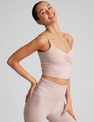 model wearing a pink cropped tank top with shirring at center front and pink high-waisted midi length leggings against a plain background.