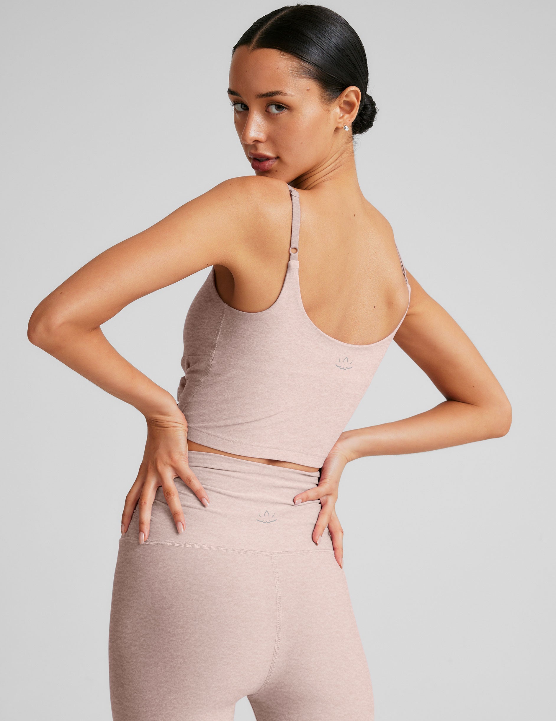 model wearing a pink cropped tank top with shirring at center front and pink high-waisted midi length leggings against a plain background.
