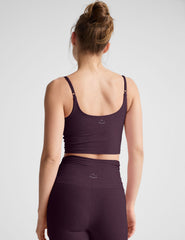 model wearing a purple cropped tank top with shirring at center front and purple high-waisted midi length leggings against a plain background.