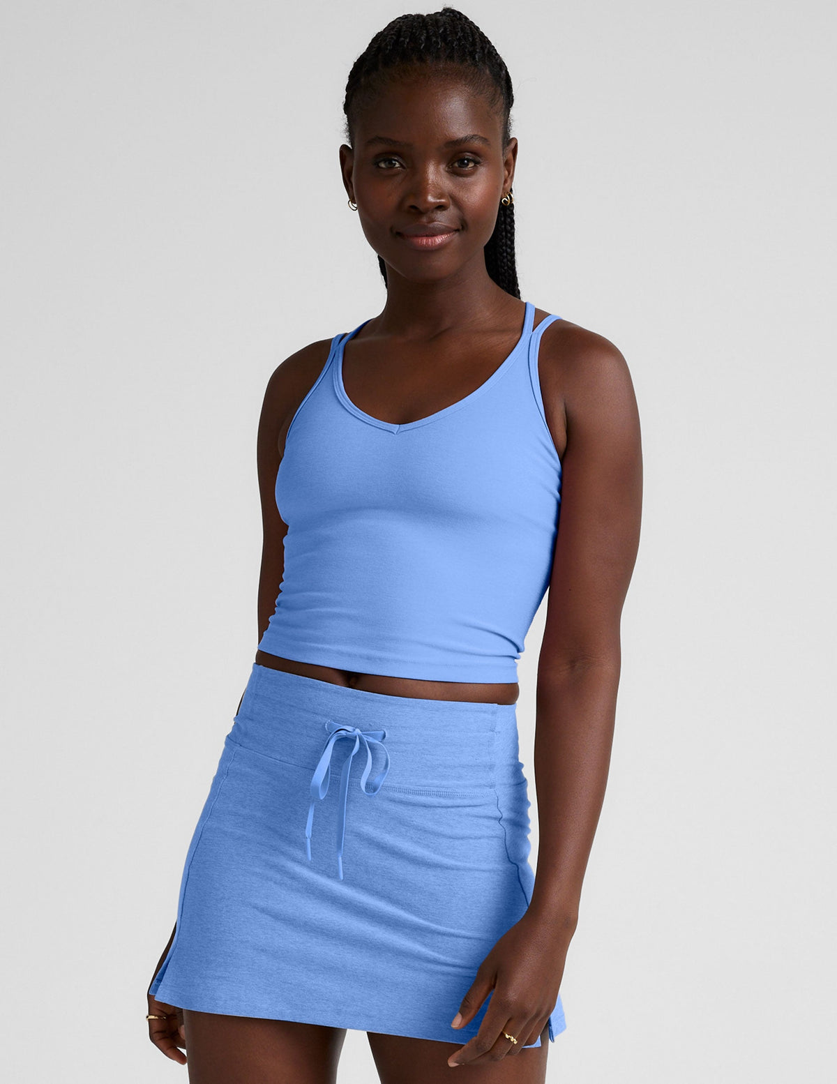 blue waist length tank top with a v-neckline and overlapping strap detail in the back.