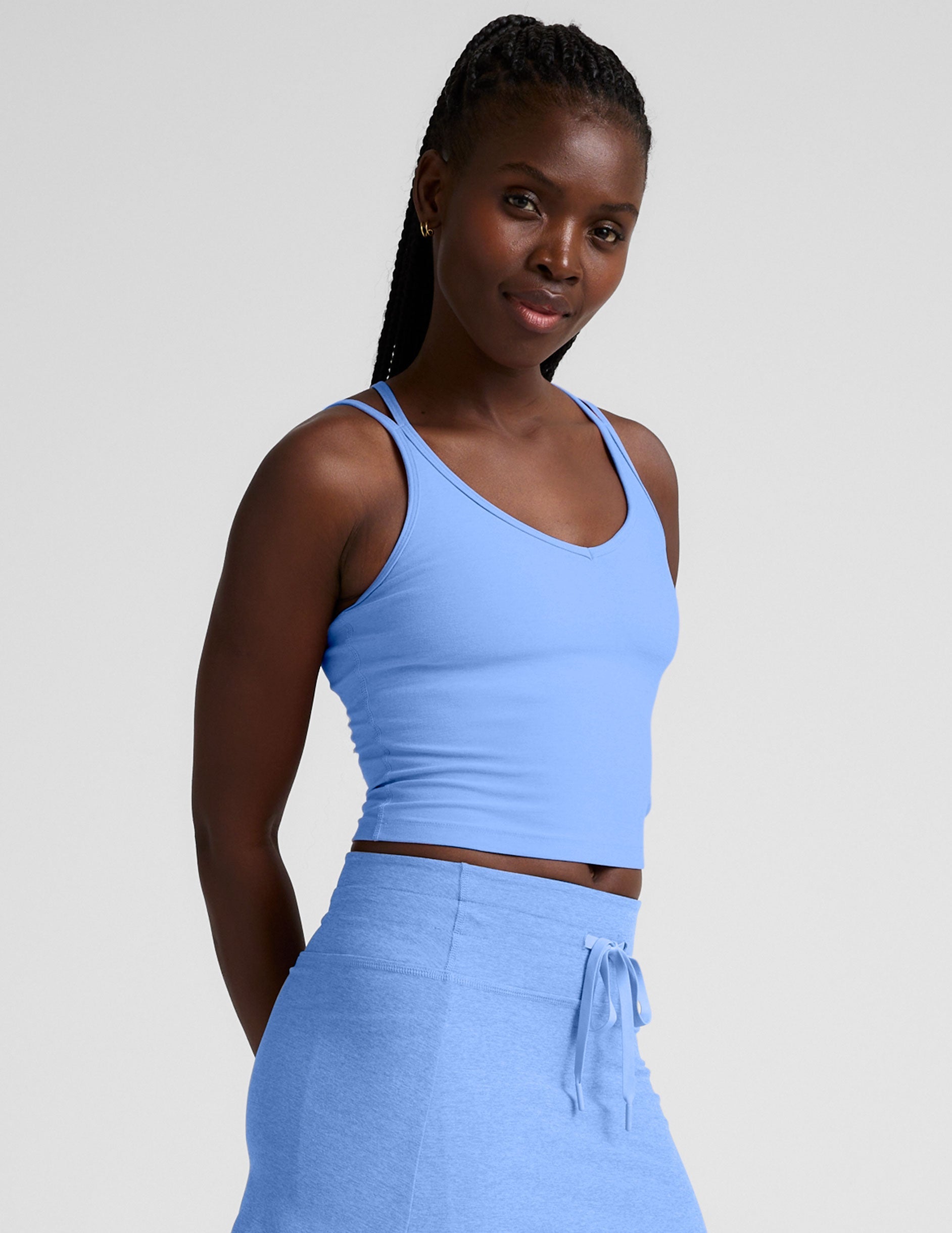 blue waist length tank top with a v-neckline and overlapping strap detail in the back.