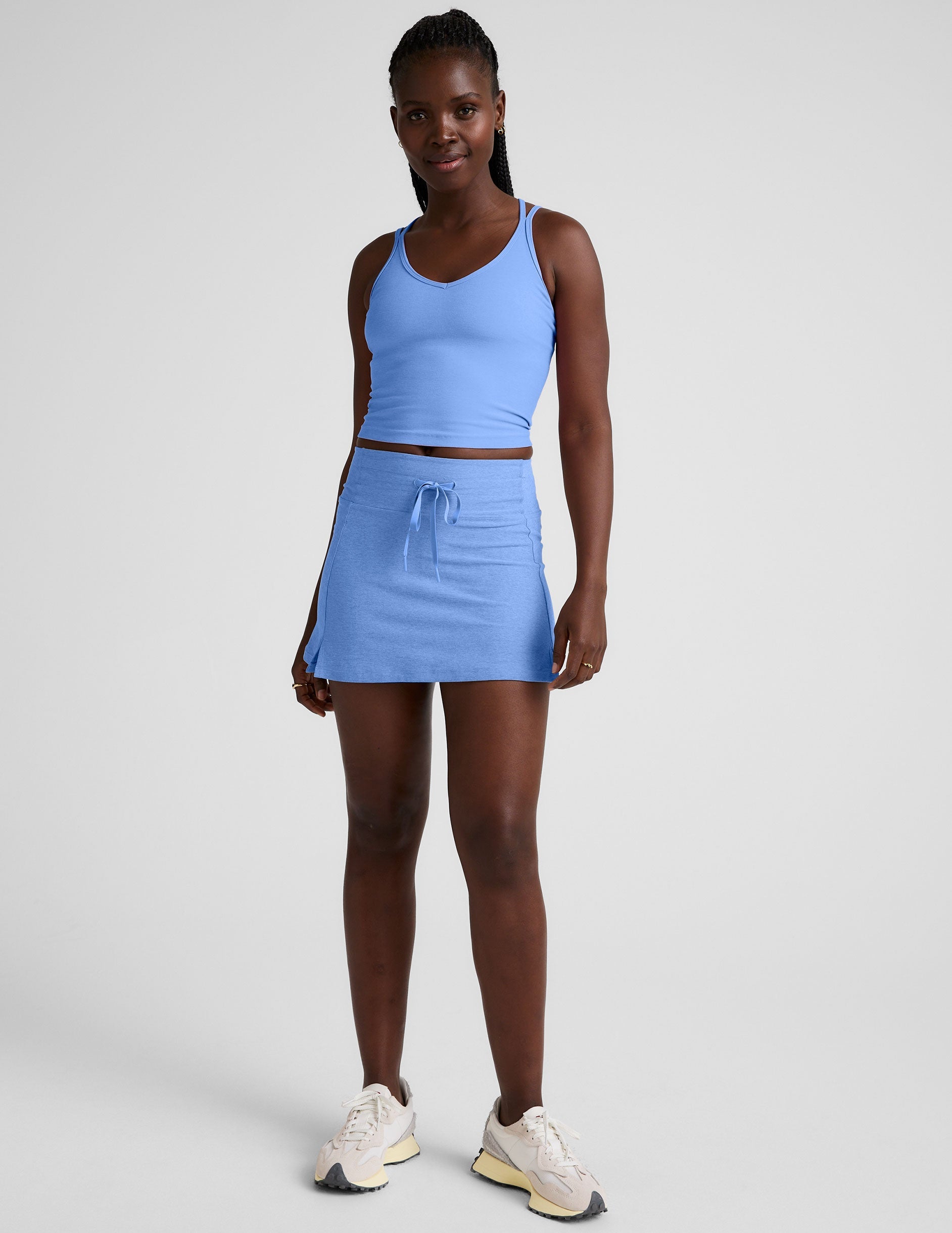 blue waist length tank top with a v-neckline and overlapping strap detail in the back.