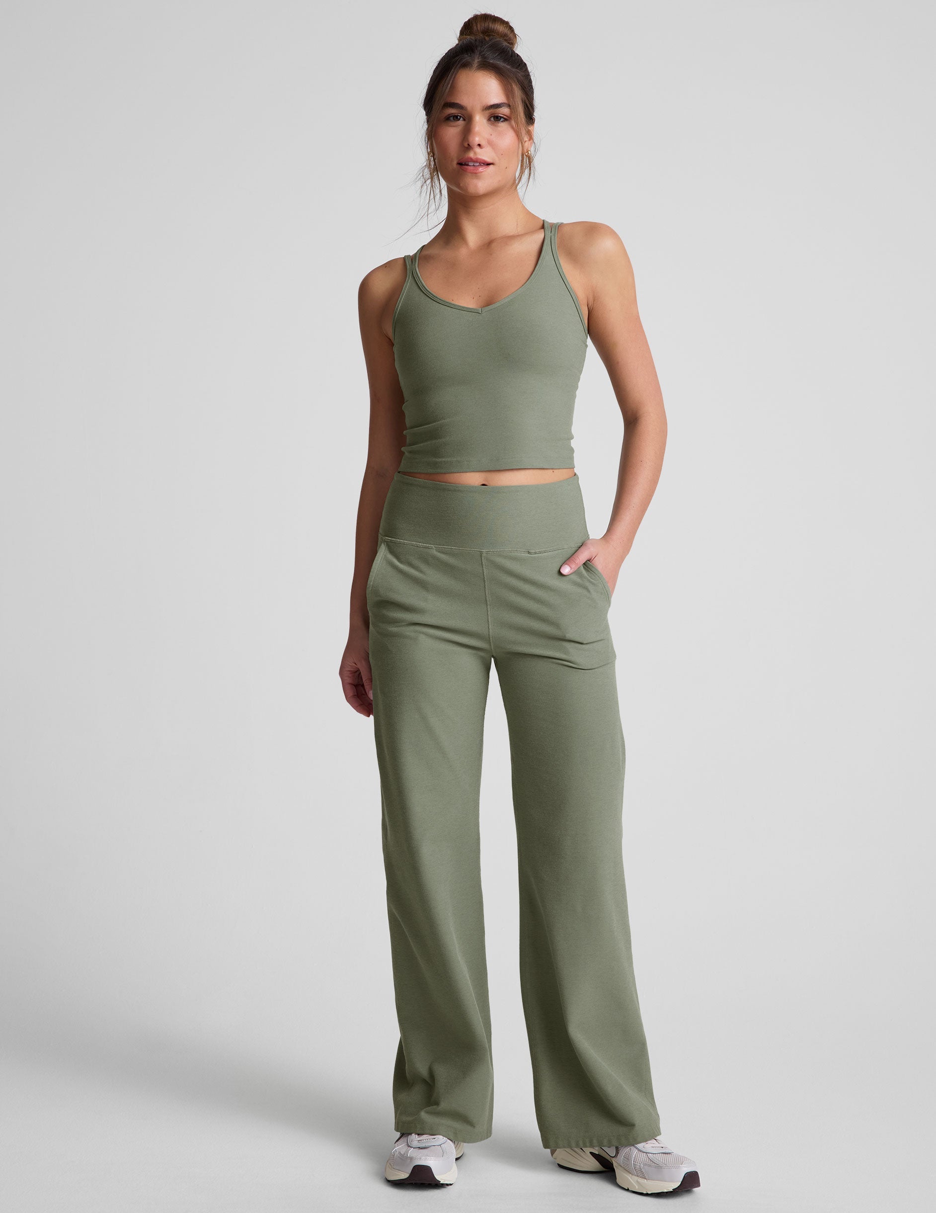 green waist length tank top with a v-neck and overlapping strap detail on back.