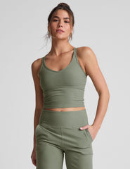 green waist length tank top with a v-neck and overlapping strap detail on back.
