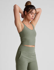 green waist length tank top with a v-neck and overlapping strap detail on back.